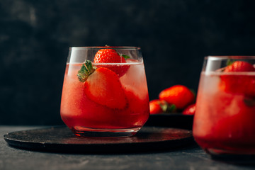two strawberry cocktail with ice on dark background