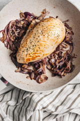 chicken breast in the pan, on caramelized red onion