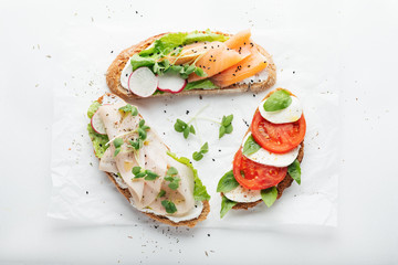 sandwiches with ham, radish, romano salad, baby basil, mascarpone cheese, caprese salad on a white background. top view.