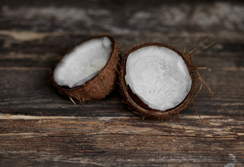 Fototapeta na wymiar Ripe half cut coconut on a wooden background. Ripe half cut coconut on a wooden background. Coconut cream and oil.