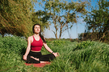 Fototapeta na wymiar Young woman doing yoga meditation outdoors