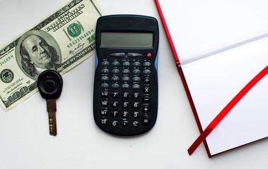 calculator key 100 dollars and notebook on white background