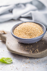 Raw  white quinoa seeds (lat. Chenopodium quinoa) on  plate with wooden spoon
