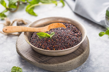 Raw  black quinoa seeds (lat. Chenopodium quinoa) on  plate with wooden spoon