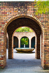 View into arched brick gallery with fountain in its centre