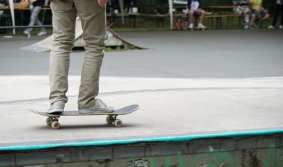 Person playing with a skateboard in a park with some people sitting on the benches