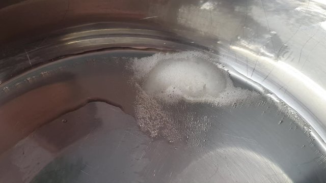 Heating and melting the piece of lard in pan and making the liquid melted hot lard for frying.