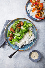 Vegan teryaki  tempeh or tempe buddha bowls  with rice, steamed broccoli, spinach  and lime on black  background. Healthy food