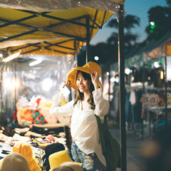 Young asian adult woman shopping yellow hat at night market.