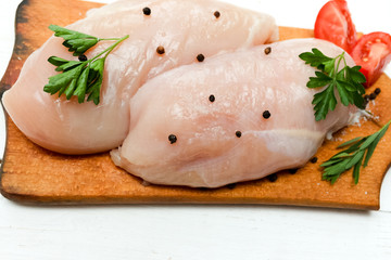 Raw chicken breast fillets on wooden cutting board with herbs and spices. 