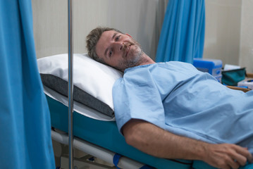 positive and hopeful hospital patient smiling before adversity - young attractive and trustful man lying on clinic bed responding to treatment and healing feeling relaxed