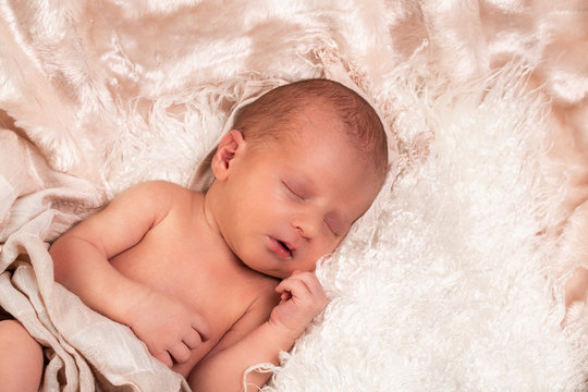 picture of a newborn baby sleeping on a blanket rolled