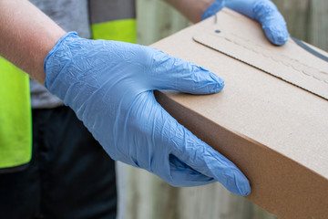Delivery driver wearing rubber gloves handing over a parcel from a distance to avoid catching...