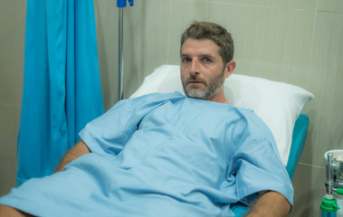 Obraz premium attractive injured man lying on hospital bed receiving treatment feeling sick and unwell after suffering accident or serious disease like cancer