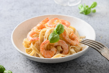 Italian pasta fettuccine with shrimps on grey. Close up.