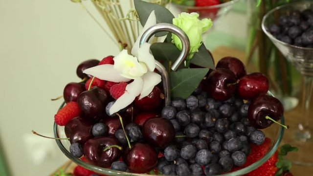 cherries, raspberries and blueberries are served on the festive table in a Nickel-plated fruit bowl
