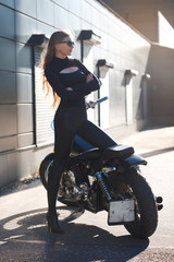 Beautiful slender girl on a motorcycle on an industrial street.