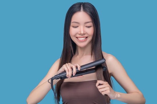 Young Asian Woman Straightening Hair And Feeling Good