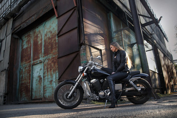 Fototapeta na wymiar Beautiful slender girl on a motorcycle on an industrial street.