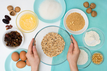 ingredients for the recipe homemade oatmeal cookies with dates, peanuts , coconut shavings, eggs, flour, salt in glazed plates on a light background. the view from the top