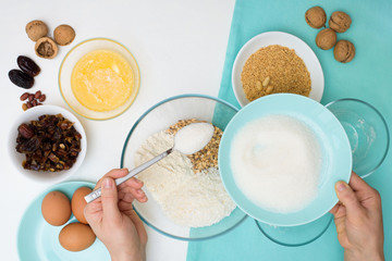 ingredients for the recipe homemade oatmeal cookies with dates, peanuts, coconut chips in glass plates on a light background. the view from the top, mixing with your hands ingredients