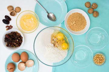 ingredients for the recipe homemade oatmeal cookies with dates, peanuts, coconut chips in glass plates on a light background. the view from the top, mixing with your hands ingredients