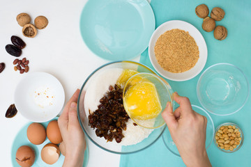 ingredients for the recipe homemade oatmeal cookies with dates, peanuts, coconut chips in glass plates on a light background. the view from the top, mixing with your hands ingredients