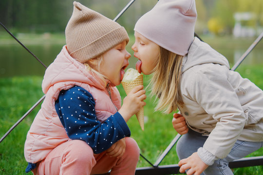 little girls 3 years old eating ice cream together in the park