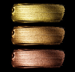 Creative brushstrokes of gold paint isolated on a black background. Gold paint texture.Acrylic gold...