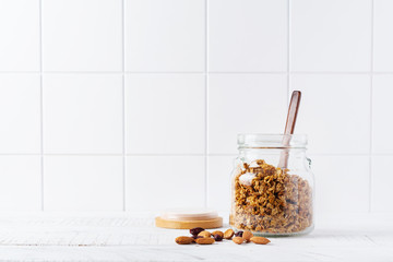 Oat granola with nuts and dried fruits to prepare a healthy breakfast on a bright kitchen table. Scandinavian white style. Selective focus.