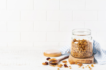 Oat granola with nuts and dried fruits to prepare a healthy breakfast on a bright kitchen table. Scandinavian white style. Selective focus.