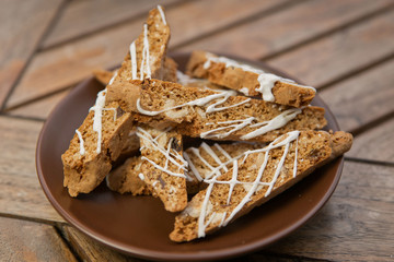 homemade Biscotti with nuts and white chocolate on a brown plate on a wooden table