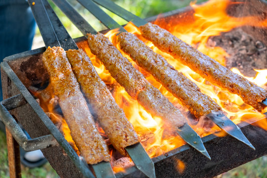 Traditional Turkish Adana  Kebap on the grill with skewers  for dinner. Turkish cuisine food culture in Turkey. Adana kebab on the mangal in nature. Picnic.
