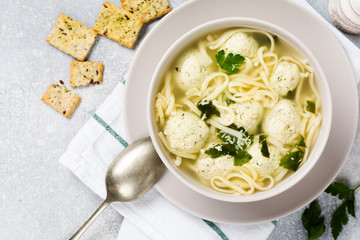 Soup with chicken meatballs and egg paste, Parmesan cheese, parsley in a ceramic bowl on a gray table background. Traditional Italian broth.  Top view.
