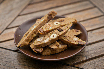 Homemade Biscotti with nuts and dark chocolate on a brown plate on a wooden table