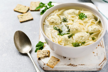 Soup with chicken meatballs and egg paste, Parmesan cheese, parsley in a ceramic bowl on a gray table background. Traditional Italian broth.  Top view.