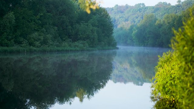4k video footage of bautiful early  morning landscape. Scenic foggy river water and fresh green trees growing on shores in countryside of Ukraine.