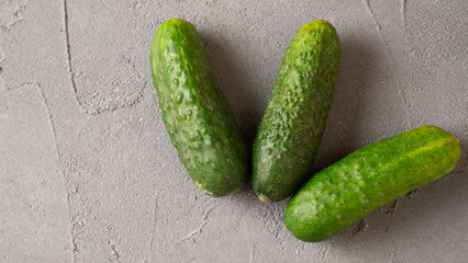 Fresh green ripe cucumbers on gray concrete background. Scattered cucumbers. Gherkins on the table close-up.