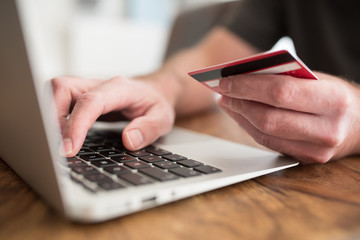 online shopping concept, person entering payment information on laptop computer holding debit or...