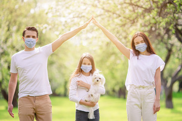 Fototapeta premium Adorable family in blooming cherry garden in masks