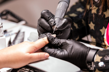 Fototapeta na wymiar Manicure care procedure, beautician applying nail drill to trim and remove cuticles