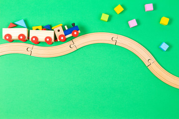 Wooden toy train with colorful blocks and wooden railway on light green background