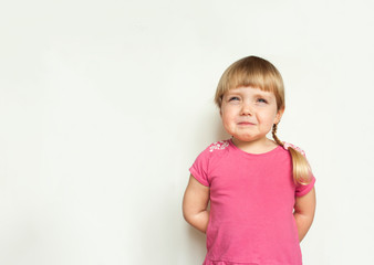 Sad cute  blonde little girl  crying in pink t-shirt on white background