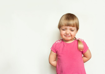 Sad cute  blonde little girl  crying in pink t-shirt on white background