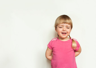 Sad cute  blonde little girl  crying in pink t-shirt on white background