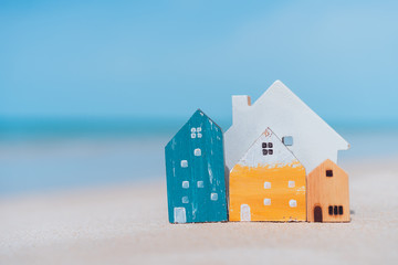 Small home model on sand beach with blue sky background.