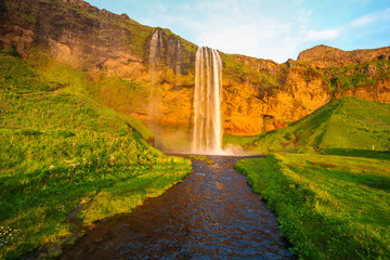 Waterfall Selandjafoss Iceland at sunset or sunrise. Beautiful waterfall in Iceland. Golden hour. Cave and waterfall. Travel in Iceland. Beautiful sky against the big waterfall. inside the water. 