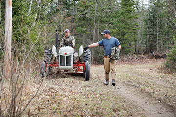 Woman driving a tractor with a man walking alongside.