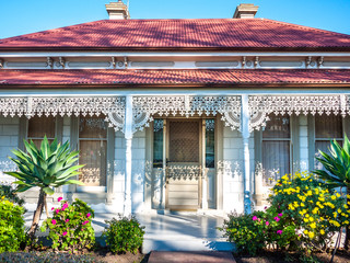 A typical Victorian-era residential house in Australia. The facade of an Australian home with verandas sporting cast-iron lacework. Roofs made from corrugated iron. Melbourne, VIC Australia.