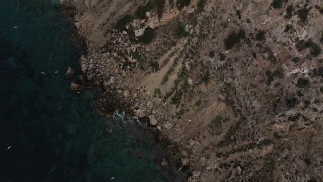 Flock of birds at sunset on a cliff. Aerial view of Cala Llonga beach. Beautiful aerial view of the bay at sunset. Ibiza, Spain.